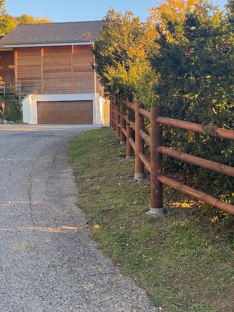 Clôture trois lisses rondes le long d'une montée menant au chalet, fabrication française SNMB — bois autoclave classe 4