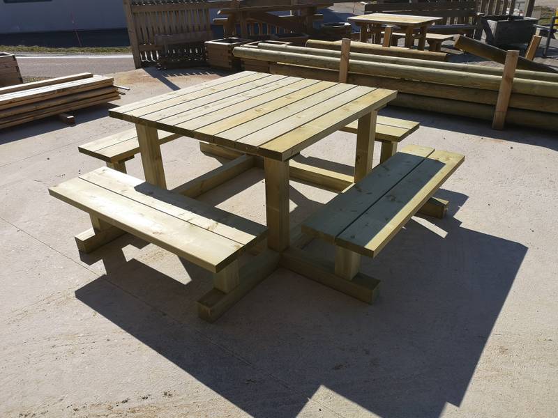 Table de pique-nique carrée huit places avec bancs intégrés, vue rapprochée en plein soleil, fabrication française SNMB — bois autoclave classe 4