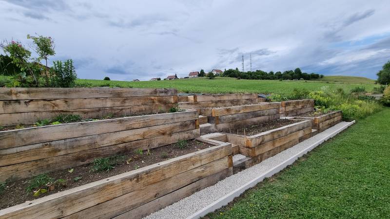 Chemin en gravillons blancs longeant la jardinière en pente en chêne, fabrication française SNMB Menuiserie Bertin