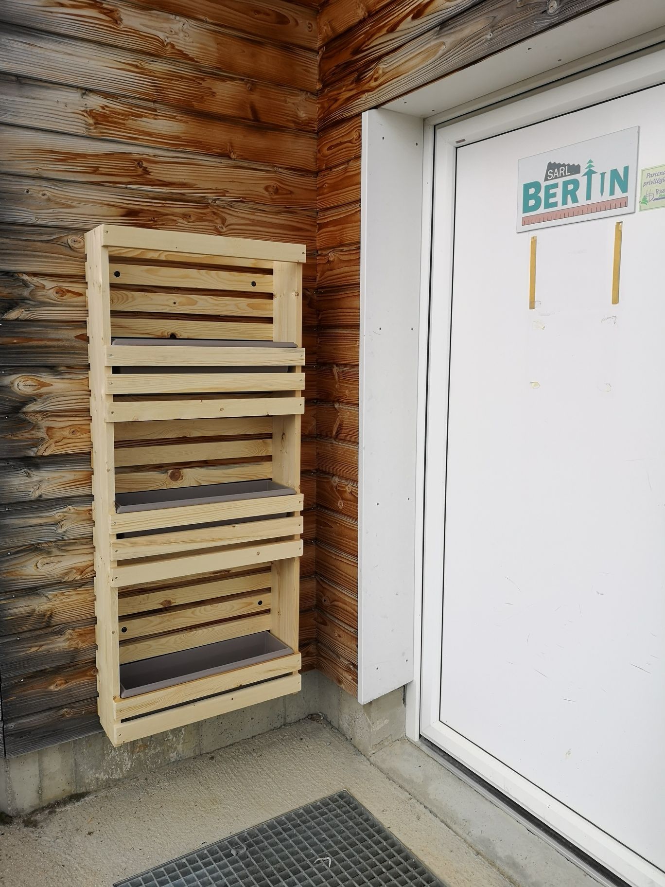 Jardinière étagère trois niveaux installée à l'entrée de la menuiserie, bardage extérieur — fabrication française SNMB Menuiserie Bertin
